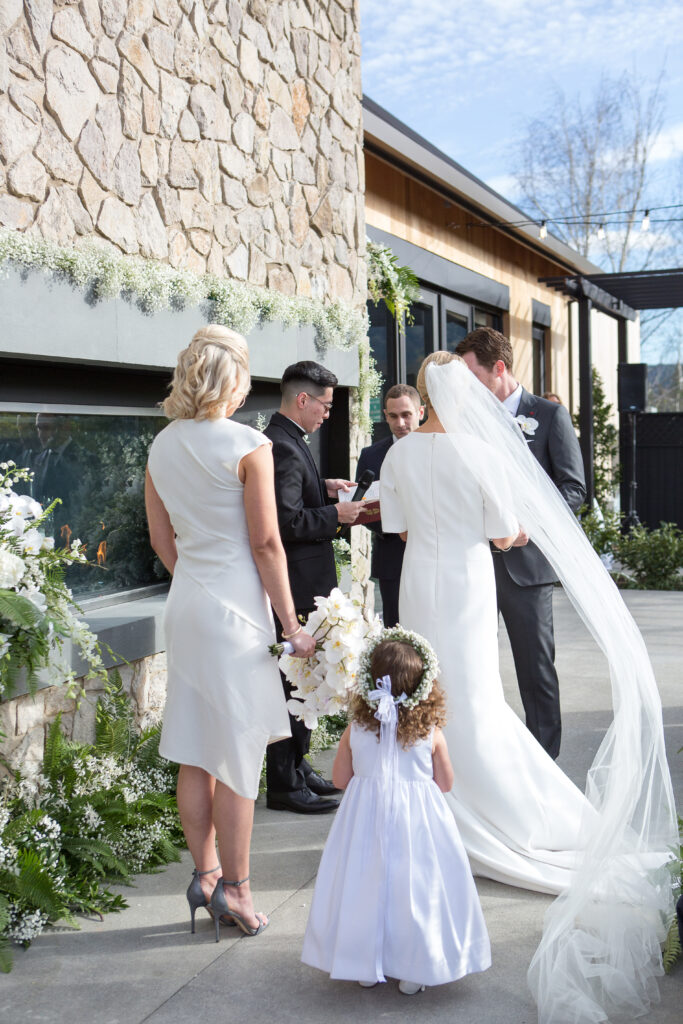 Intimate outdoor wedding ceremony at Estate Yountville with couple exchanging vows and guests gathered, photographed by a Napa Valley wedding photographer.