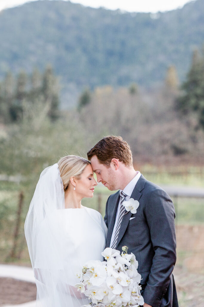 Bride and groom portrait at Estate Yountville with vineyard and hills in the background, photographed by a Napa Valley wedding photographer.