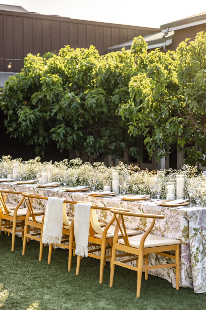 Elegant outdoor wedding table at Carneros Resort and Spa set beneath olive trees with wooden chairs, soft linens, and neutral floral arrangements in Napa Valley