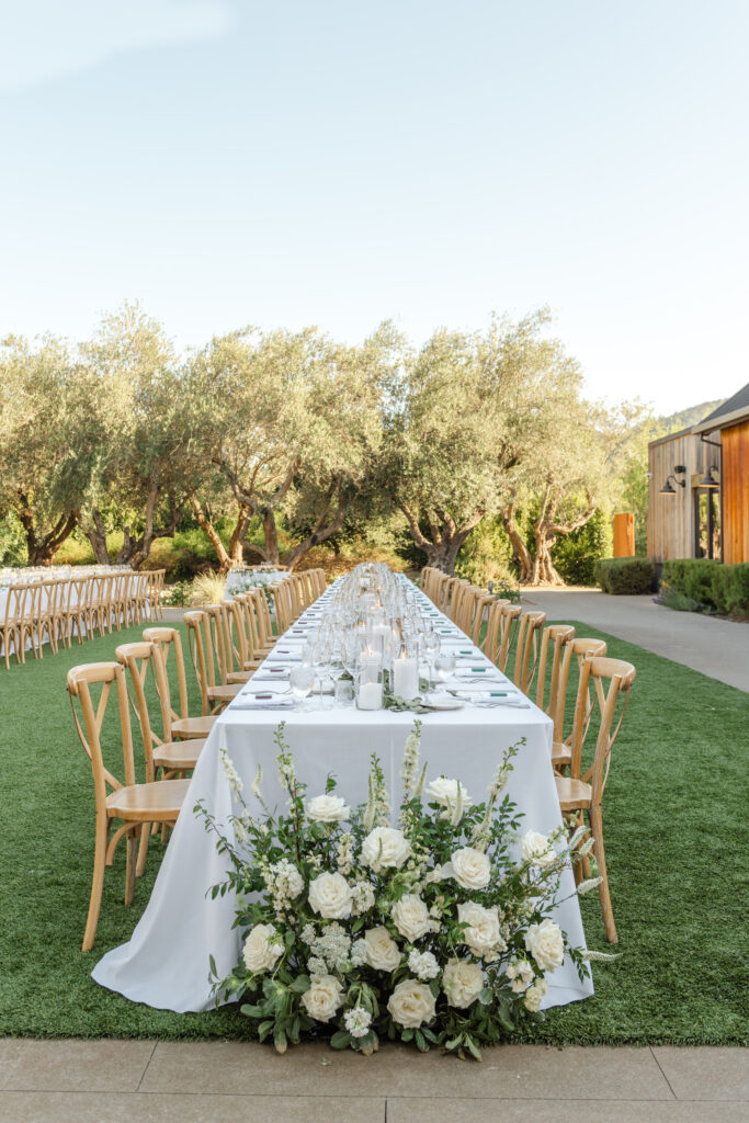 Long outdoor wedding reception table with white linens and floral arrangements at Estate Yountville in Napa Valley.