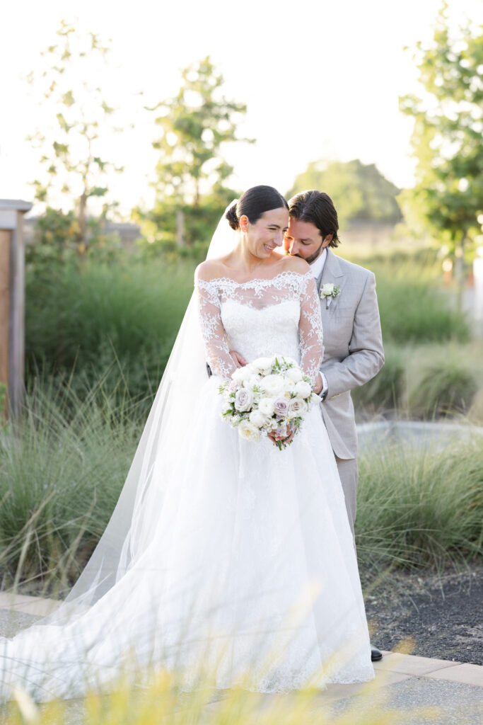 Bride and groom embracing during golden hour at Carneros Resort and Spa, surrounded by soft greenery and natural light in Napa Valley