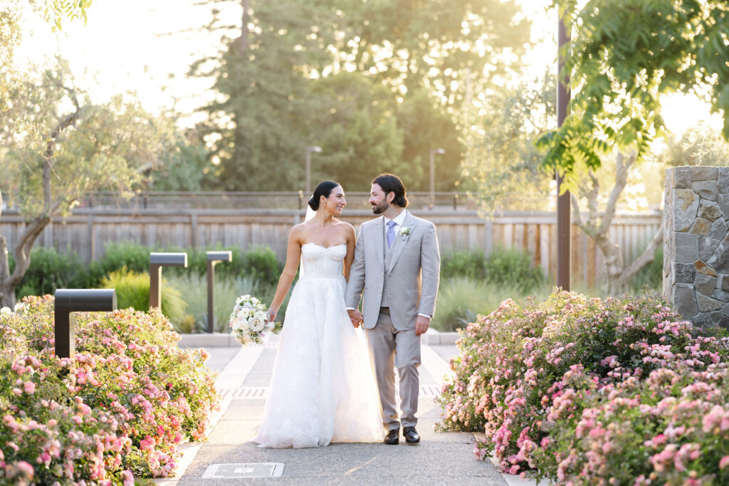 Bride and groom walking hand in hand through landscaped gardens at Carneros Resort and Spa during golden hour in Napa Valley