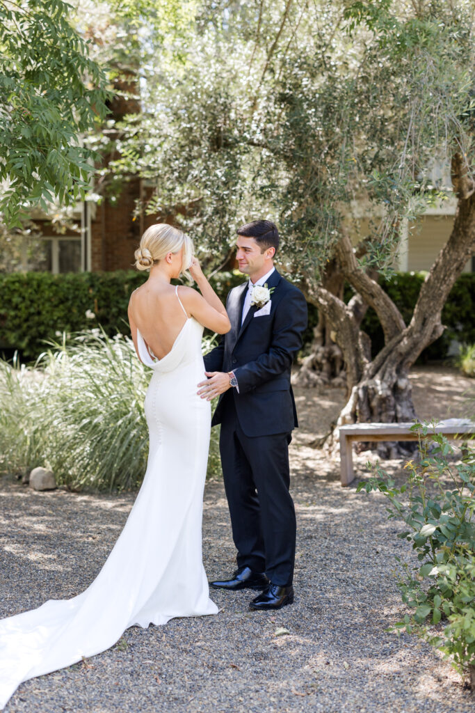 Bride and groom share an intimate first look beneath olive trees at Estate Yountville, captured by a Napa Valley wedding photographer in natural light.