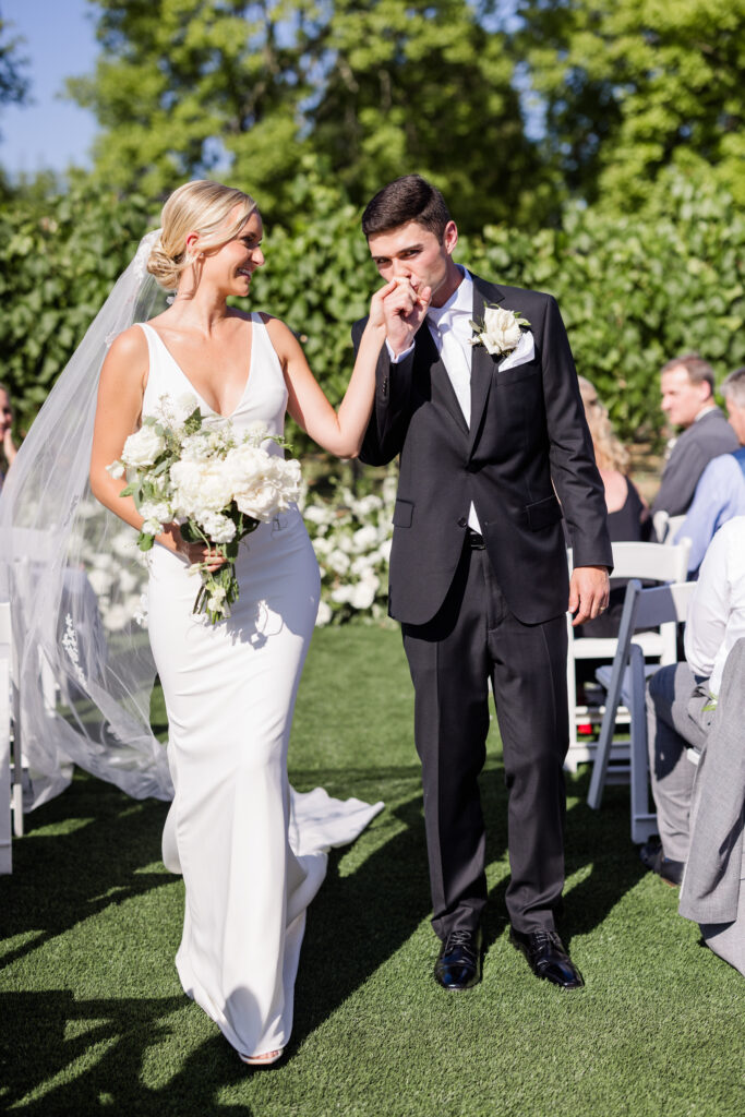 Newly married couple walking down the aisle at their outdoor Estate Yountville wedding ceremony, surrounded by vineyard views and guests in Napa Valley.