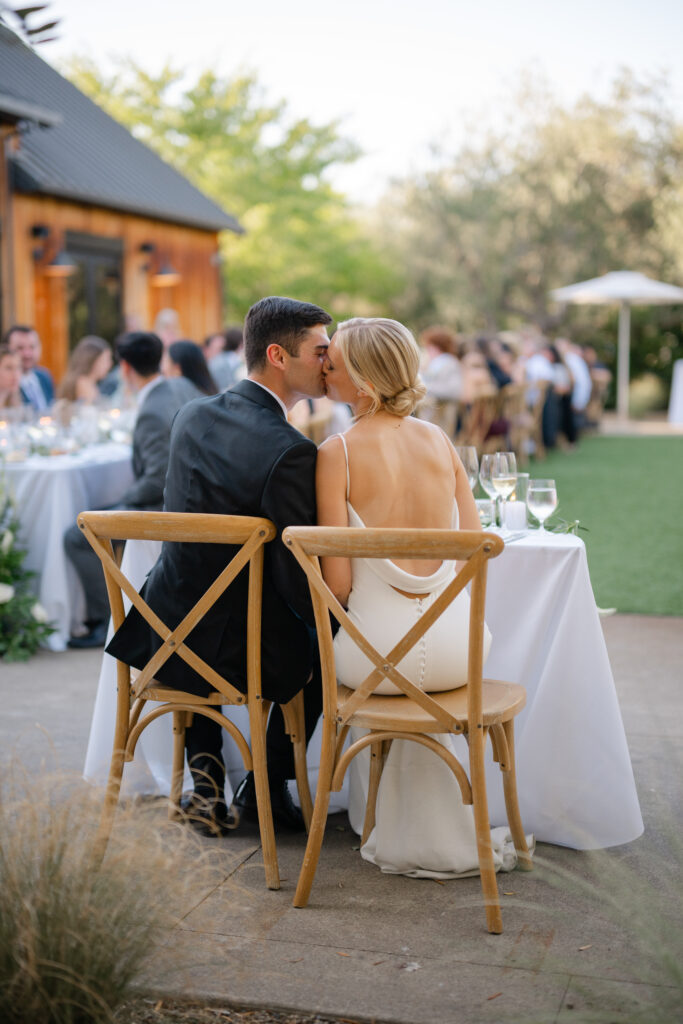 Bride and groom sharing a quiet kiss during outdoor wedding reception at Estate Yountville in Napa Valley