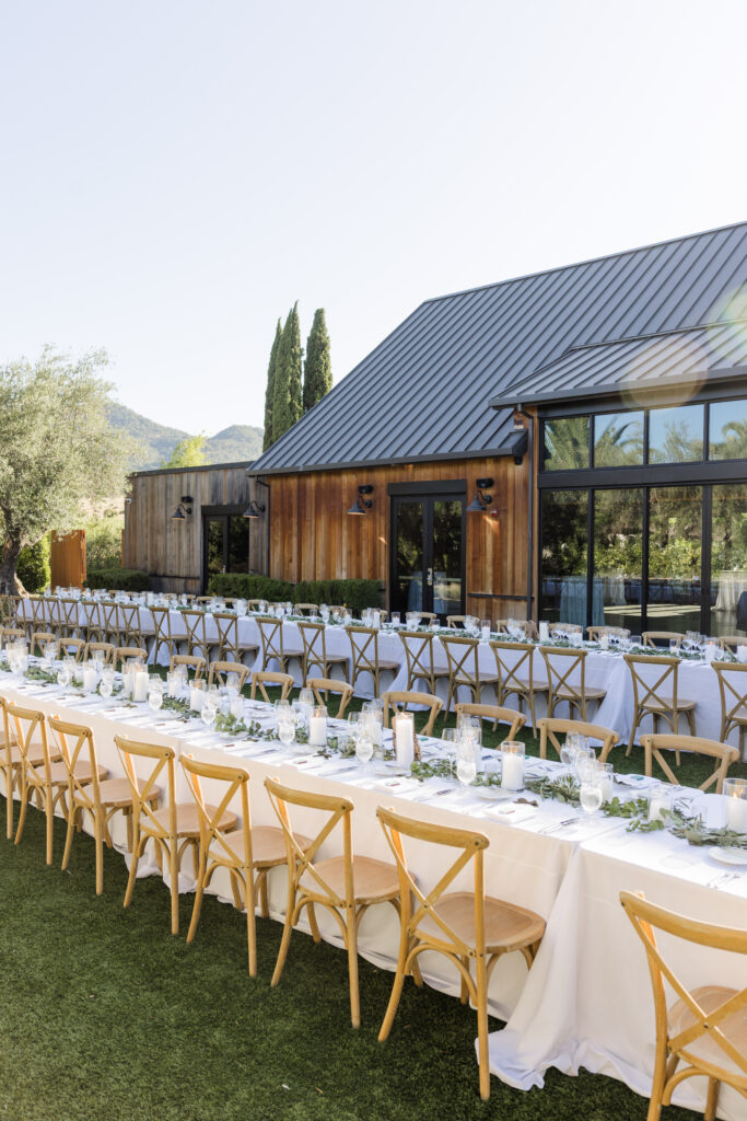 Outdoor wedding reception with long tables and wooden chairs at Estate Yountville wedding venue in Napa Valley