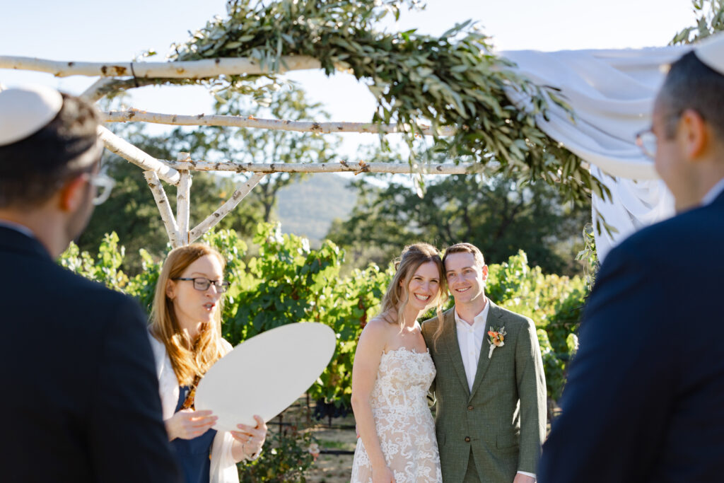 Couple smiling during an intimate vineyard ceremony beneath a chuppah at Estate Yountville wedding in Napa Valley