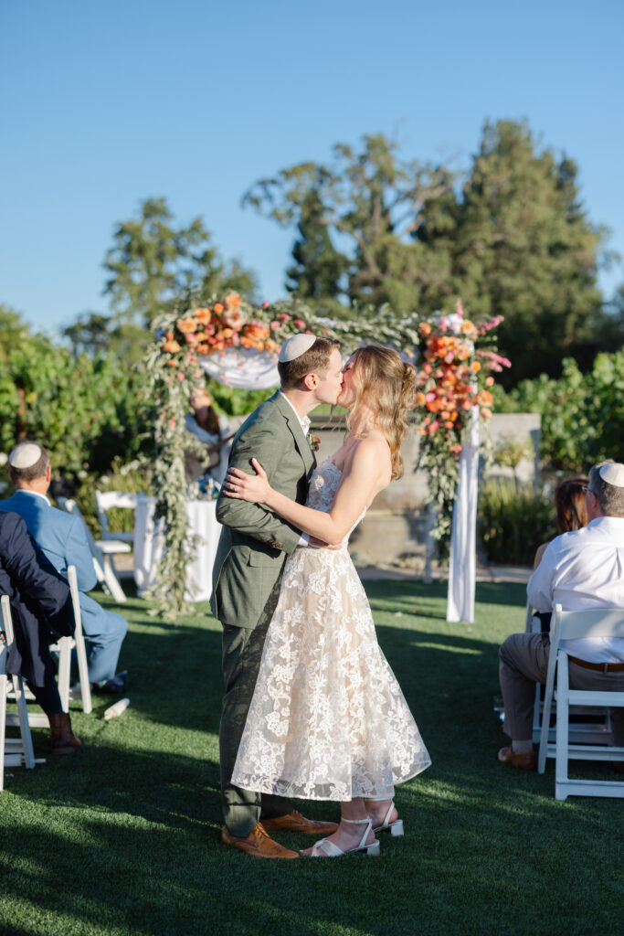 Couple sharing their first kiss during a vineyard wedding ceremony at Estate Yountville