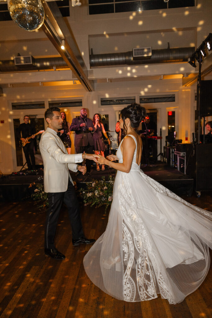 Bride and groom dancing during their wedding reception, twirling on a candlelit dance floor with live band and disco ball at Carneros Resort and Spa in Napa Valley.