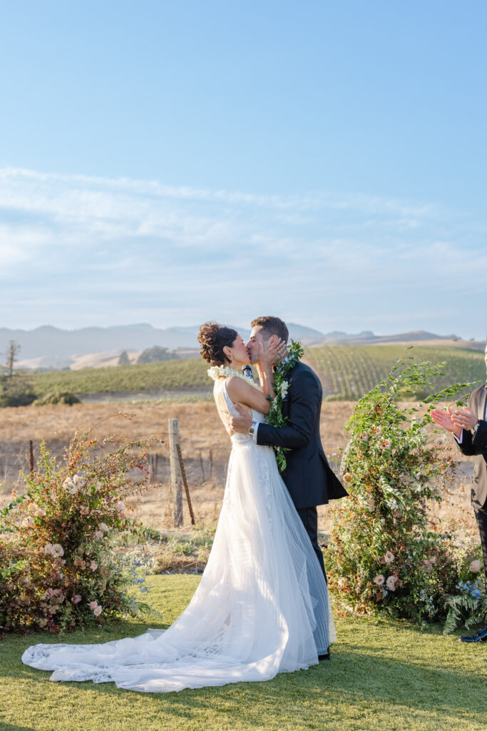 Bride and groom sharing their first kiss during the wedding ceremony at the Hilltop Lawn at Carneros Resort and Spa in Napa Valley Wine Country.