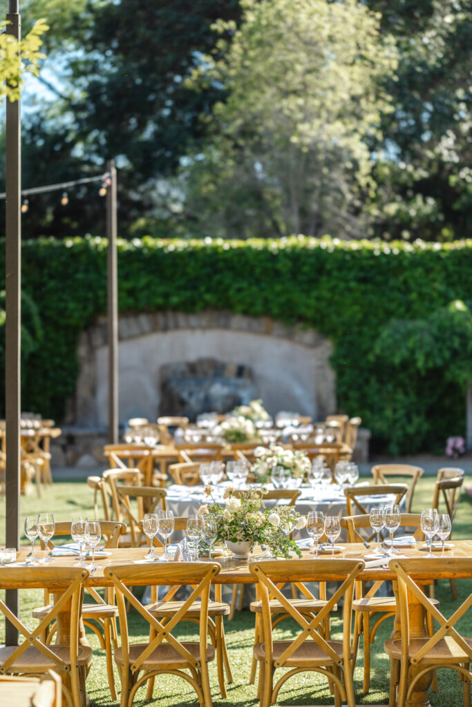 Outdoor wedding reception setup at the Pavilion at Estate Yountville with wooden tables and café lighting