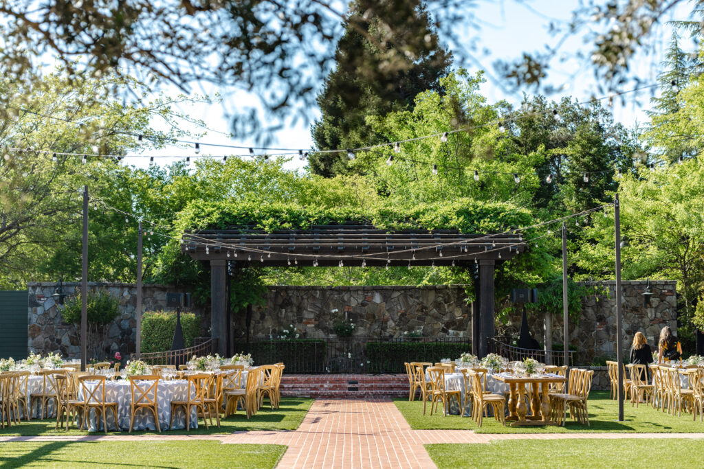 Outdoor wedding reception setup at the Pavilion at Estate Yountville with long tables, café lights, and garden surroundings