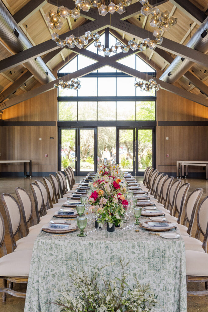 Long banquet table set inside The Social at Estate Yountville with vaulted ceilings and modern chandeliers
