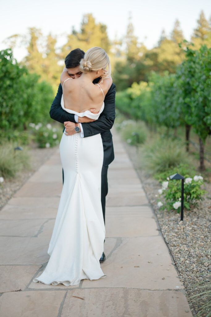 Intimate portrait of the newlyweds embracing on the vineyard walkway at Estate Yountville