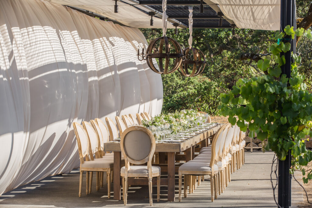 Outdoor reception table under draped canopy and chandeliers at Montage Healdsburg wedding venue