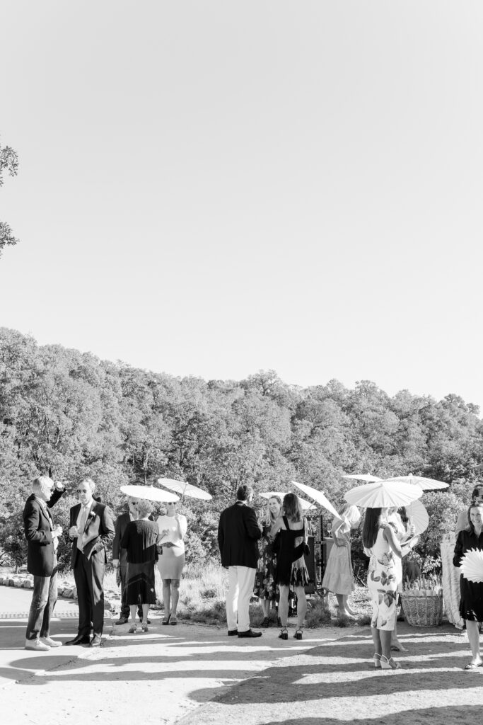 Black and white photo of wedding guests holding parasols during ceremony at Montage Healdsburg