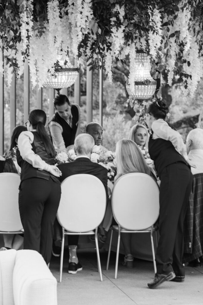 Black and white photo of servers assisting guests during reception at Montage Healdsburg wedding