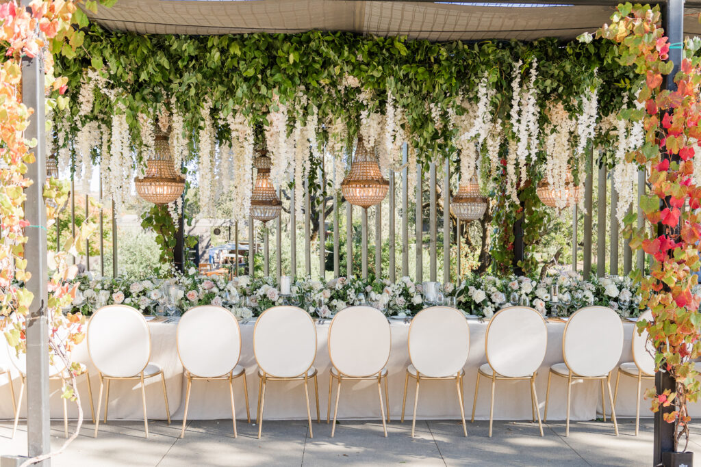 Elegant head table with greenery and white chairs at Montage Healdsburg reception