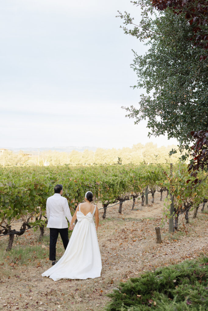 A bride and groom share a kiss beneath towering palm trees during their Carneros Resort wedding portraits in Napa Valley, photographed by Suzanne Karp Photography