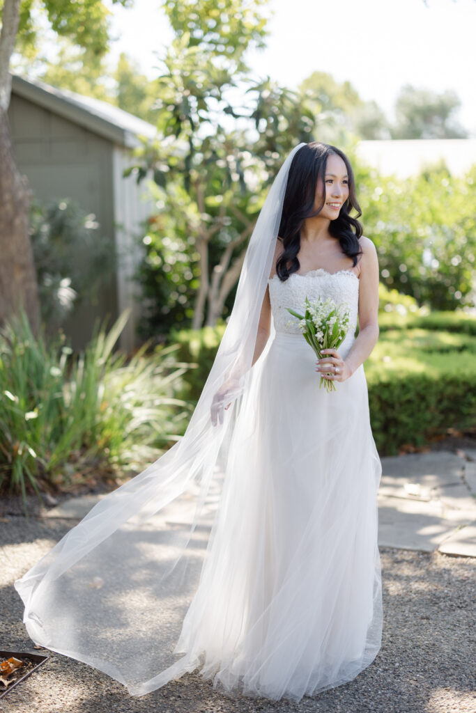 A bride in a strapless gown with a flowing veil holds her bouquet during golden hour portraits at a Napa Valley wedding, photographed by Suzanne Karp Photography