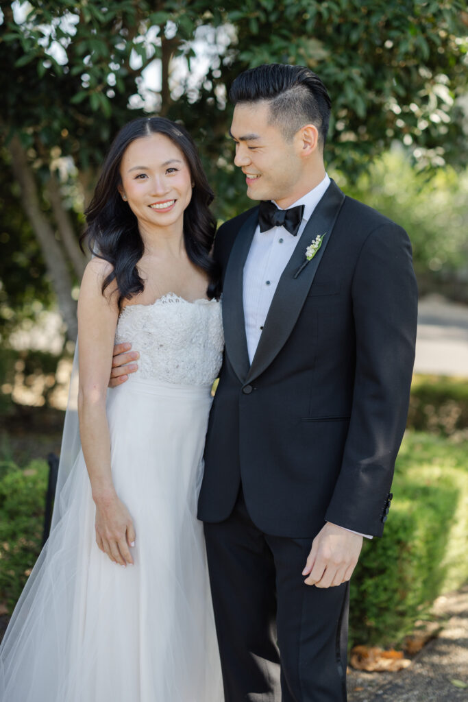 A bride and groom pose together during their Napa Valley wedding portraits surrounded by lush greenery, photographed by Napa wedding photographer Suzanne Karp