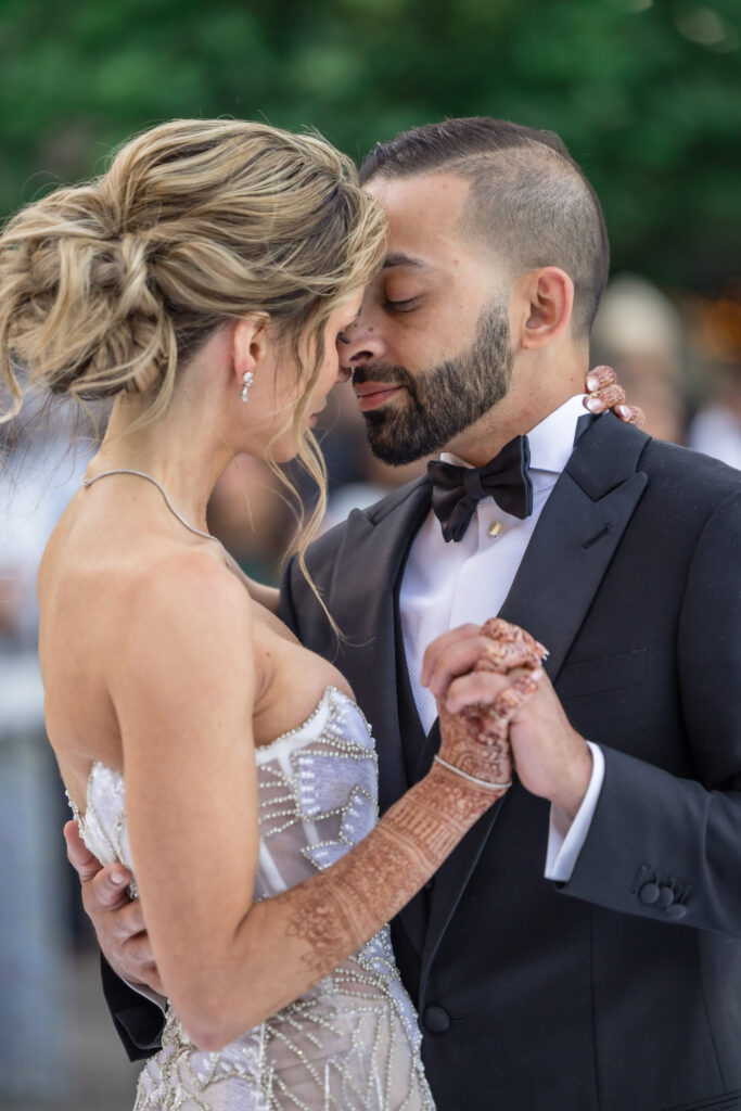 A bride and groom share an intimate slow dance during their Napa Valley wedding reception at Beaulieu Gardens in Rutherford, the bride in a beaded fringe dress with henna still visible on her hands, photographed by Suzanne Karp Photography