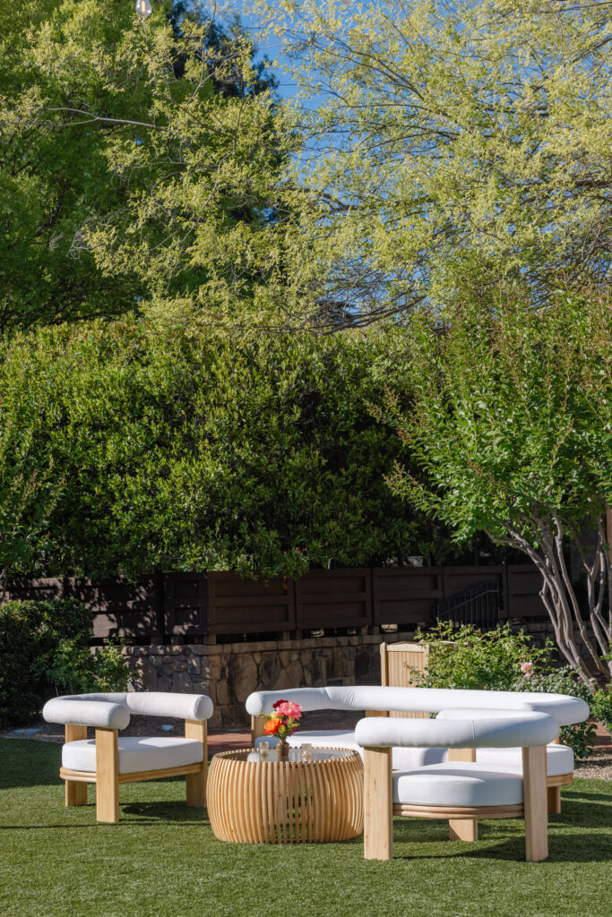 A modern white lounge setup with curved sofas and rattan coffee tables styled on the lawn at Estate Yountville during a Sangeet celebration in Napa Valley, photographed by Suzanne Karp Photography