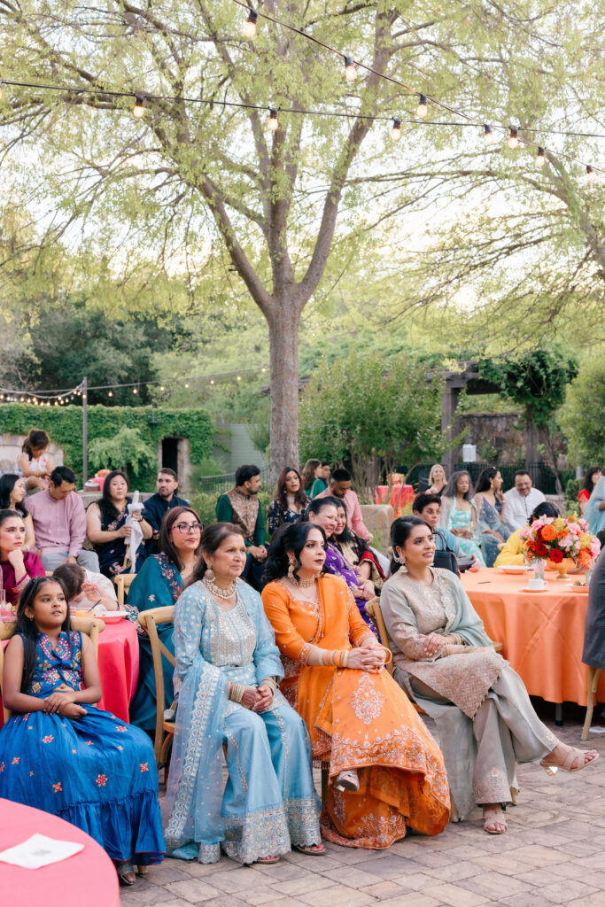 Guests dressed in colorful Indian attire are seated on the lawn watching performances during the Sangeet celebration at Estate Yountville in Yountville, Napa Valley, photographed by Napa Valley wedding photographer Suzanne Karp