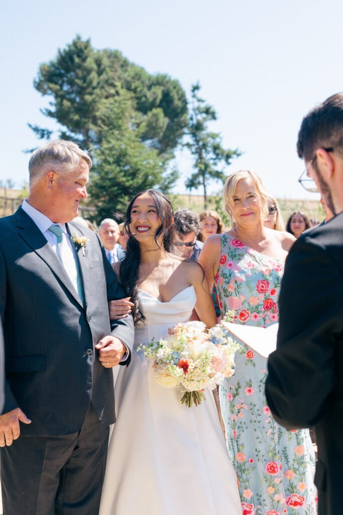 A bride laughs joyfully with her parents immediately after her wedding ceremony during a Northern California wedding photographed by Napa Valley wedding photographer Suzanne Karp