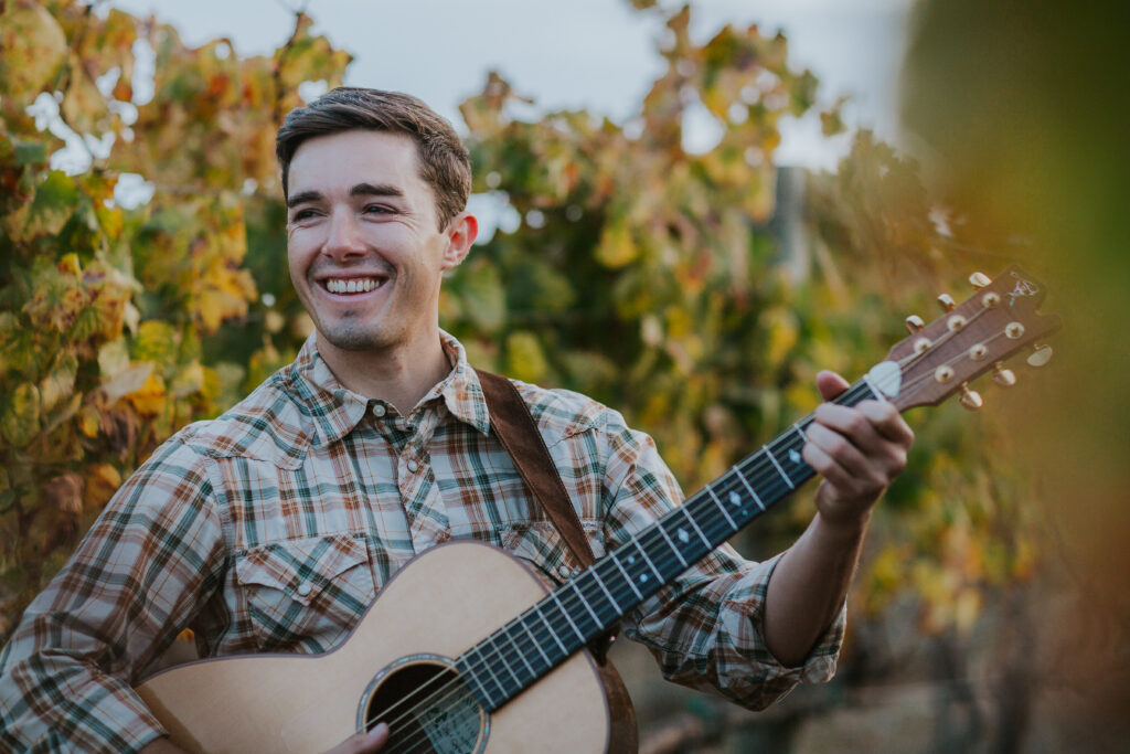 Musician Justin Diaz plays acoustic guitar during a Napa Valley elopement ceremony in black and white