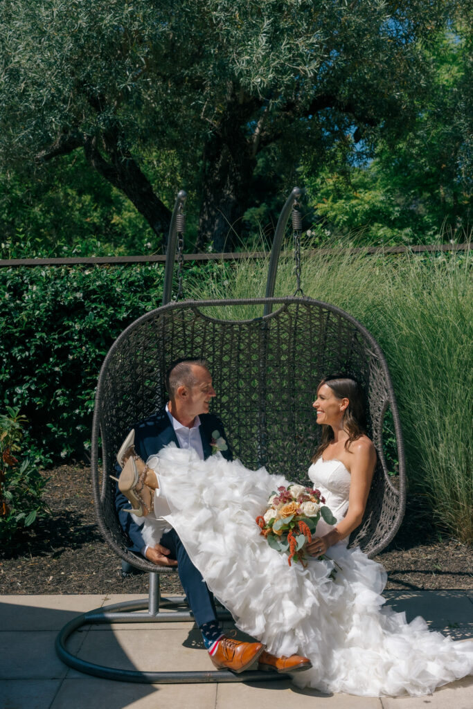 Newlyweds share a hanging chair beneath an olive tree in the gardens at Bardessono after their Yountville elopement